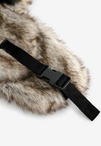 Faux-Fur-Produkt in Braun- und Beigetönen, mit einem schwarzen verstellbaren Gurt und einer Kunststoffschnalle. Weiche Textur mit natürlichen Farbvariationen.