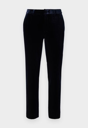 Pantalones de terciopelo azul oscuro con un frente plano, presillas para cinturón y un diseño ajustado. La textura suave y el brillo sutil mejoran la apariencia.