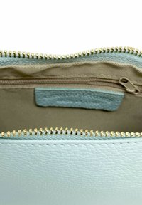 Ljusblå l äderpung med en guldfärgad dragkedja. Inuti finns ett beige foder och en liten ficka med dragkedja för extra förvaring.