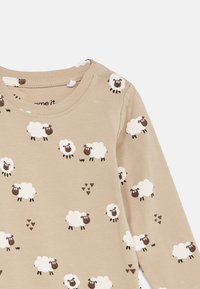 Μπεζ μπλουζάκι μωρού με μακριά μανίκια, διακοσμημένο με λευκά κινούμενα πρόβατα και μικρά τριγωνικά σχέδια εκτυπωμένα σε όλο το ύφασμα.