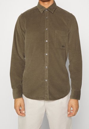 Olivgrünes Cordhemd mit Knopfleiste, einer Brusttasche und silbernen Knöpfen. Es verfügt über einen strukturierten Stoff mit vertikalen Rillen.