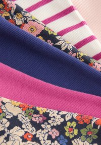 Tissus pliés empilés comprenant des rayures roses sur fond blanc, des motifs floraux multicolores, un bleu marine uni et des textures côtelées roses unies.