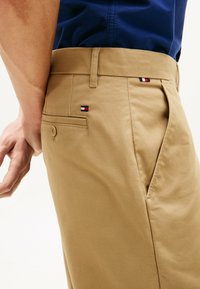 Pantalon kaki avec une texture lisse, coupe slim, doté de poches latérales et d'une poche arrière avec un petit logo coloré.