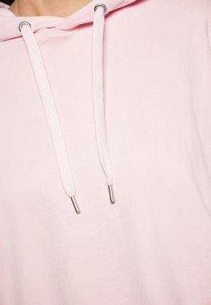 Lichtroze hoodie met een trekkoordsluiting met zilveren metalen uiteinden. Zacht stof en een gladde textuur met een ontspannen pasvorm.