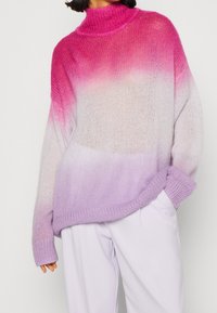 Pull tricot surdimensionné présentant un dégradé de couleurs : du rose au lavande. Il comporte un col montant, des poignets côtelés et une surface douce et texturée.