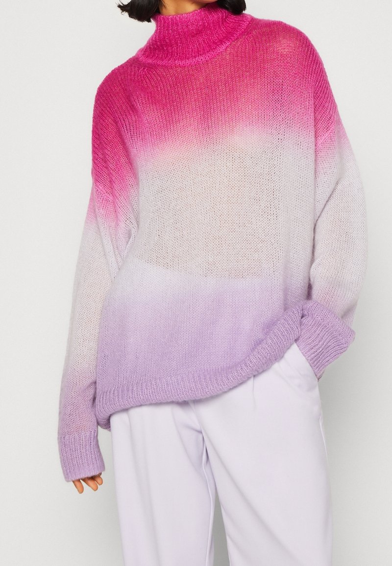 Pull tricot surdimensionné présentant un dégradé de couleurs : du rose au lavande. Il comporte un col montant, des poignets côtelés et une surface douce et texturée.