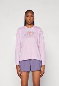 Pitkähihainen laventelinvärinen urheilupaita, jossa on punainen ja sininen vuoristograndiikka, yhdistettynä purppuraisiin shortseihin. Silkkinen pinta, rento istuvuus.
