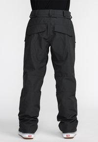 Pantalons de neige noirs avec une coupe décontractée, fabriqués en tissu texturé. Dotés de poches arrière doubles et de coutures renforcées au niveau des genoux.