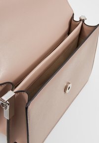 Różowa skórzana torebka o gładkim wykończeniu, z centralną przegrodą, zapięciem na zatrzask w srebrnym kolorze oraz czarnymi akcentami.