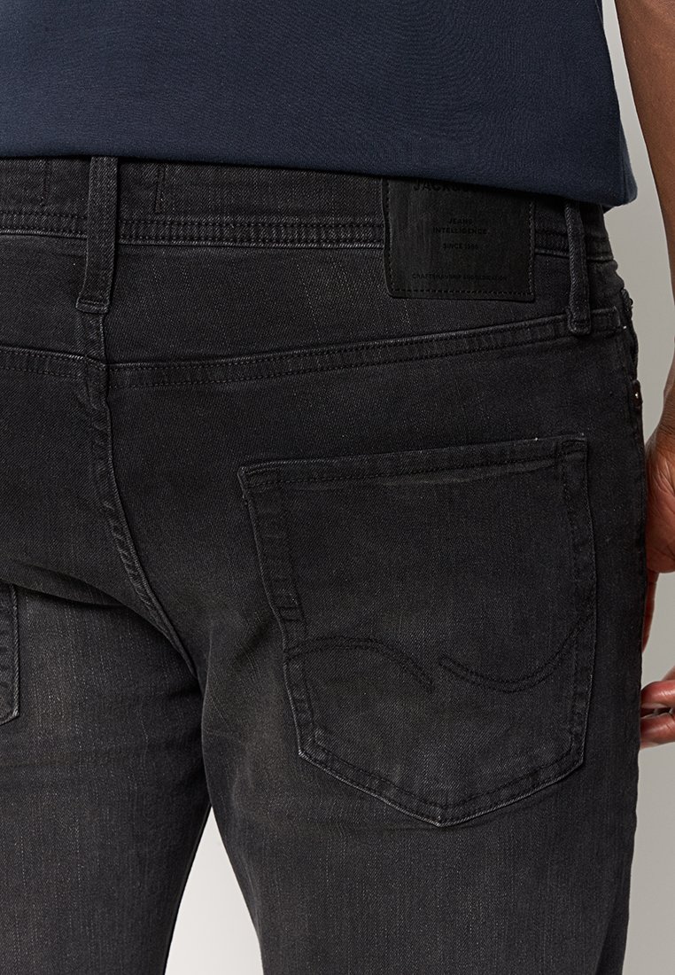 Schwarze Denim-Jeans im Slim-Fit, mit einer Gesäßtasche und einem strukturierten Stoff. Enthält ein schwarzes Leder-Patch am Taillenbund.