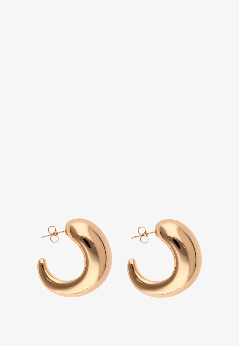 Metaliczne kolczyki w złotym odcieniu o zakrzywionym, błyszczącym wzorze. Posiadają gładką powierzchnię i zapięcie na sztyft. Każdy kolczyk ma kształt półksiężyca.