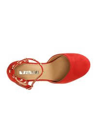 Scarpa con tacco alto in suede rosso, con punta arrotondata, cinturino alla caviglia con accenti dorati e una fodera interna liscia.