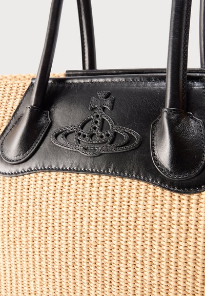 Πλεκτή μπεζ τσάντα χειρός με μαύρο δερμάτινο περιθώριο, λαβές και κεντημένο έμβλημα σφαίρας και σταυρού στην εμπρόσθια πλευρά.