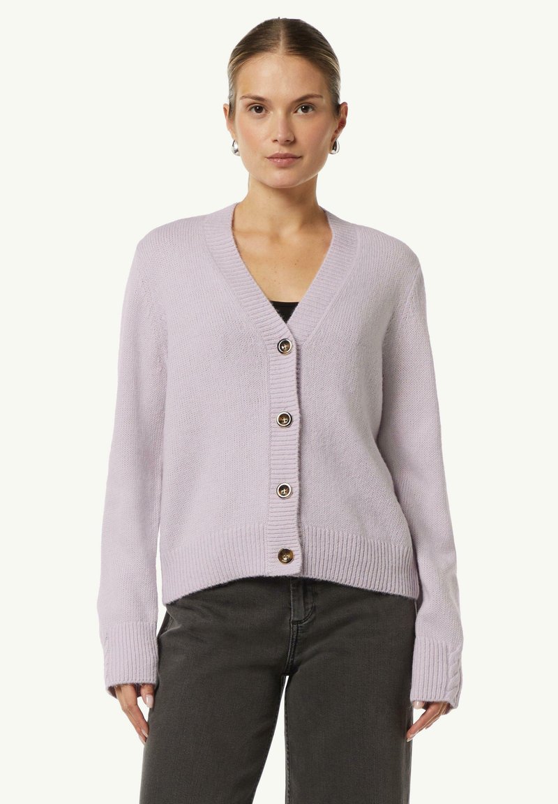 Lila Strickjacke mit V-Ausschnitt, gerippten Bündchen und fünf braunen Knöpfen auf der Vorderseite. Weicher Stoff, cropped Länge.