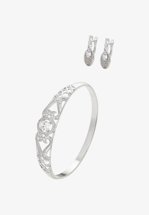 Sølvarmbånd med indviklet filigrandesign og central klar sten. Par af sølvringe med oval form og små, klare ædelstensdetaljer.