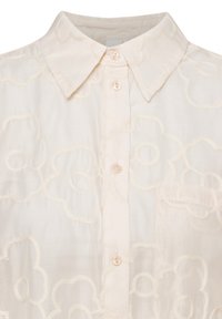 Helle beige Bluse mit floralem Stickmuster, klassischem Kragen und einer Brusttasche, mit Perlenknöpfen aus weichem Stoff.