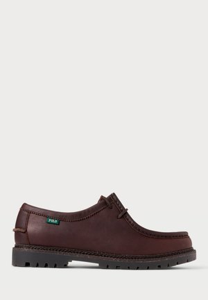 Scarpa in pelle marrone con punta arrotondata, cuciture a contrasto e un'etichetta verde "POLO". Suola in gomma testurizzata per una migliore aderenza.