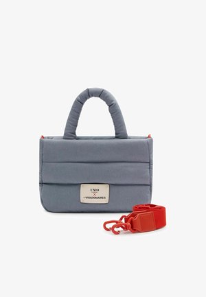 Sac à main matelassé gris avec poignées supérieures, une étiquette rectangulaire et une sangle détachable rouge vif avec clips à côté.
