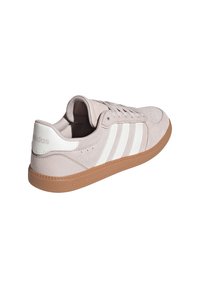 Hellrosa Wildleder-Sneaker mit weißem Drei-Streifen-Design, Gummisohle in Karamellfarben und strukturierten Paneel-Akzenten. „Adidas“-Markenlogo an der Ferse.