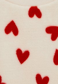 Pulover tricotat din material moale crem, cu modele în relief de inimioare roșii împrăștiate pe suprafață și guler cu dungi.