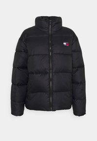 Black puffer jacket with a high collar, quilted design, zippered front, and a small logo patch on the left chest. Soft, shiny texture.
