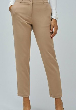 Pantalones beige a medida con una textura suave, que cuentan con dos bolsillos laterales, cintura de tiro medio y pierna ligeramente ajustada.