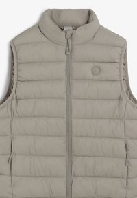 Veste matelassée sans manches de couleur gris clair, avec col montant, fermeture éclair à l'avant et petit logo rond sur le côté gauche de la poitrine.