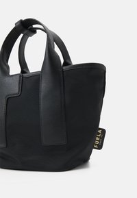 Borsa a tracolla nera con dettagli in pelle testurizzata e tessuto liscio. Presenta manici corti e un'etichetta del logo dorata. Design moderno e strutturato.
