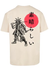 Beige t-shirt featuring a black samurai graphic, dual swords, and Japanese text with a red circular background. Cotton material, short sleeves.