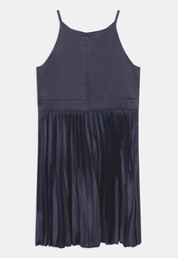 Námořnické saténové šaty se spaghetti ramínky, s přiléhavým tělem a plisovanou sukní. Zavírání na zip na zadní straně, hladká textura a splývavý silueta.