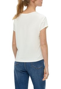 Biała, krótki rękaw T-shirt z okrągłym dekoltem i luźnym krojem, zestawiony z niebieskimi dżinsami z wysokim stanem z tylnymi kieszeniami.