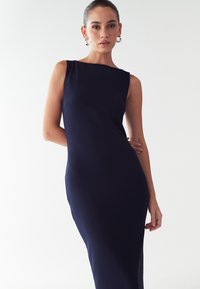 Tums zilas bez Piedurknēm Kleita ar pieguļošu dizainu. Gluda auduma ar nelielu spīdumu, beidzas zem ceļgala; minimālistisks kakla izgriezums.