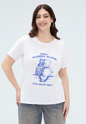 Femme souriante aux cheveux foncés portant un T-shirt blanc avec une impression bleue de deux chats qui s'enlacent et le texte « JE VEUX PAS TRAVAILLER, JUSTE MIAOU MIAOU ».