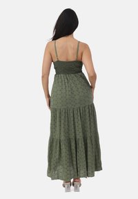 Lunga maxi dress verde con corpetto arricciato, spalline sottili e gonna a strati caratterizzata da un motivo testurizzato e sottili ritagli.