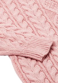 Pulover tricotat din fir gros, de culoare roz deschis, cu modele texturate și manșete cu nervuri. Materialul tricotat are un aspect confortabil și pufos.