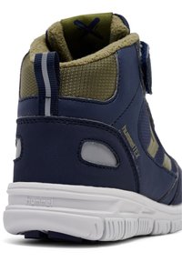 Hoge sneaker in marineblauw met olijfgroene accenten, textielstof, glad leer en een witte rubberen zool. Klittenbanddetails zichtbaar.