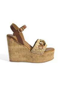Sandale à talon compensé en cuir marron avec une base en liège, une bande en paille tressée, des éléments en métal doré et une sangle réglable à la cheville.