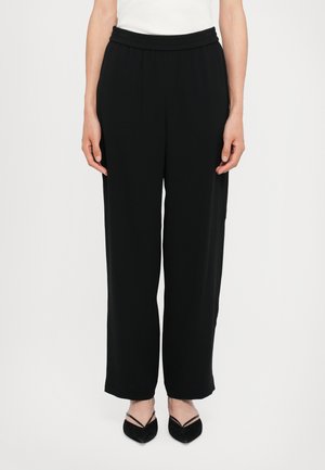 Black, wide-leg trousers with an elastic waistband, made from a smooth fabric. Features a loose fit that drapes to the ankles.
