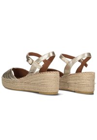 Gouden metallic espadrille-wedges met een geweven jute platform, verstelbare enkelbandjes en een gestructureerde bovenkant met een golvend ontwerp.