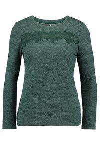 Zielona bluzka z długim rękawem, wykonana z teksturowanej tkaniny, z koronkowym panelem na wideoozczu zdobionym misternymi wzorami kwiatowymi.