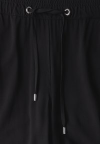 Pantalons noirs à taille élastique, dotés d'un cordon de serrage avec embouts en métal, d'une texture lisse et d'un design décontracté.