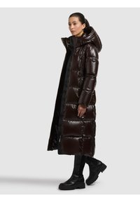 Pikk, läikiv pruun täispuhutud mantel kapuutsiga, millel on tikitud osad ja lukuga taskud. Sobitatud mustade põlveni ulatuvate saapadega.