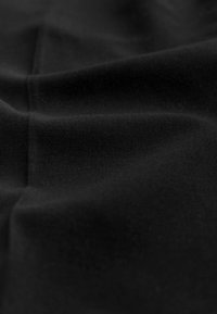 Zwarte stof met een gladde textuur, met subtiele kreukels en een uniforme, effen kleur over het geheel. Geen zichtbare patronen of ontwerpen.