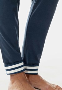 Pantalones de lounge de algodón en color marina con puños de rayas blancas y marinas, que presentan una textura suave y un diseño de pierna ajustada.