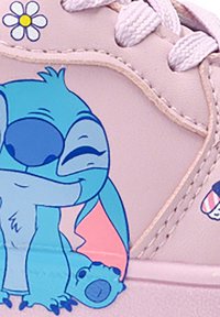 Zapatilla de color rosa claro con un gráfico de un personaje de dibujos animados en azul, diseño de cordones y detalles en blanco, con un adorno floral cerca de la lengüeta.