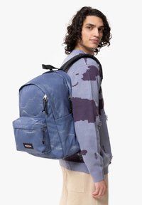 Zaino blu con motivo, dotato di una tasca frontale, spallacci imbottiti e una forma strutturata. Realizzato in un tessuto durevole e testurizzato con cerniere.