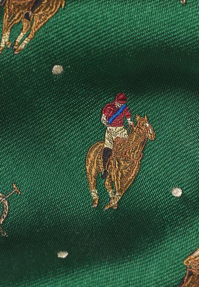 Πράσινο ύφασμα με κεντημένους παίκτες πόλο με κόκκινα πουκάμισα και μπεζ παντελόνια που ιππεύουν καφέ άλογα, διάσπαρτο με μικρές λευκές κεντητές κουκίδες.