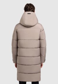 Lys beige pufferjakke med høj krave, horisontalt quiltet design, lange ærmer og skulderdetaljer. Lavet af glat, vandafvisende materiale.
