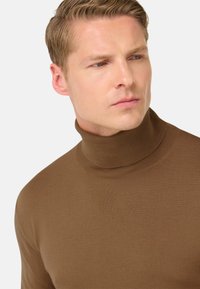 Rjav pulover s turtleneck ovratnikom v rebrasti teksturi, z ozko prilegajočim ovratnikom in dolgimi rokavi, narejen iz mehkega, raztegljivega materiala.