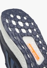 Sola de sapato com uma superfície de borracha texturizada em azul marinho, apresentando uma entressola branca e um destaque laranja na área de amortecimento.